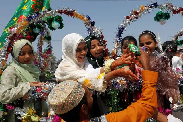 Girls reach out to collect snacks during the celebrations to mark the birth anniversary of Prophet Mohammad, in Karachi, Pakistan on September 29, 2023. (Photo by Akhtar Soomro/Reuters)