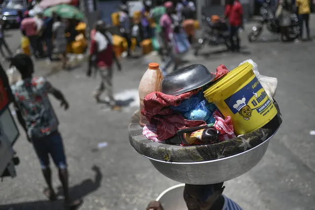 A woman carries a basin with her belongings at the Petion-Ville market in Port-au-Prince, Haiti, Sunday, July 11, 2021, four days after the assassination of Haitian President Jovenel Moise. (Photo by Matias Delacroix/AP Photo)