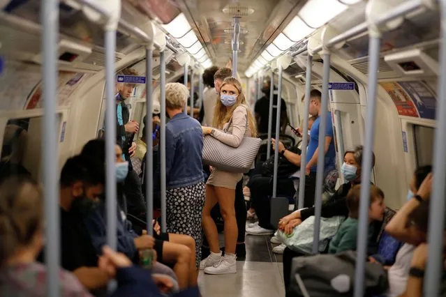 People, many wearing face coverings to combat the spread of the coronavirus, travel on the Jubilee line of the London Underground on August 9, 2021. After updated guidance from British health regulators, coronavirus vaccinations have been extended to those aged 16 and 17 without underlying health issues, but not to younger healthy teenagers as in many other Western countries. (Photo by Tolga Akmen/AFP Photo)