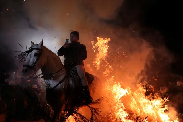 A man points a phone to himself riding a horse through flames during the annual “Luminarias” celebration on the eve of Saint Anthony's day, Spain's patron saint of animals, in the village of San Bartolome de Pinares, northwest of Madrid, Spain, January 16, 2019. (Photo by Susana Vera/Reuters)