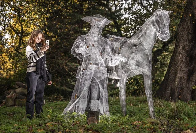 On Monday, October 31, 2022 Eva Deprez takes a photograph of “Highwayman and Horse” that forms part of the Ghosts in the Gardens display in Museum Gardens in the York, one of the ghostliest cities in Europe. The spooky trail from the York Business Improvement District (BID) features ghostly sculptures in the gardens at Treasurer's House, The Merchant Adventurers Hall, Middleton's Hotel, Barley Hall, The Artists Garden and St Anthony's Garden. (Photo by Danny Lawson/PA Images via Getty Images)