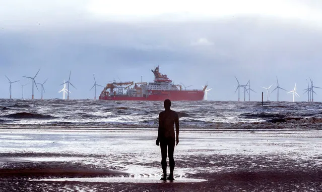 Polar research ship, the RRS Sir David Attenborough, sails out of the River Mersey past Antony Gormley's art installation “Another Place” at Crosby, north west England on November 03, 2020. In November, the shipyard will formally hand over the ship to the Natural Environment Research Council (NERC). Early next year the ship will undertake ice trials in the Arctic, and in November 2021 make its maiden voyage to Antarctica. (Photo by Peter Byrne/PA Wire Press Association)