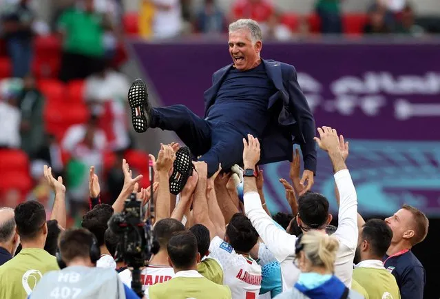 Iran's players celebrate their victory with Iran's Portuguese coach Carlos Queiroz during the Qatar 2022 World Cup Group B football match between Wales and Iran at the Ahmad Bin Ali Stadium in Al-Rayyan, west of Doha on November 25, 2022. (Photo by Amanda Perobelli/Reuters)