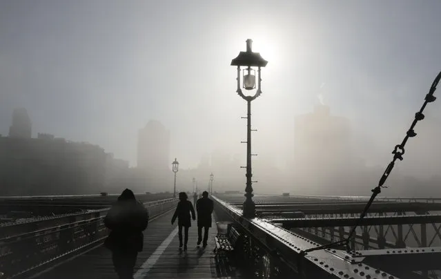 Fog mutes the Brooklyn skyline as it rolls onto the Brooklyn Bridge on Wednesday, January 15, 2014, in New York. Fog challenged morning travellers in parts of New York and New Jersey. (Photo by Bebeto Matthews/AP Photo)