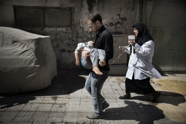 A Syrian man carries his wounded daughter outside a hospital in the northern city of Aleppo on September 18, 2012. (Photo by Marco Longari/AFP Photo)