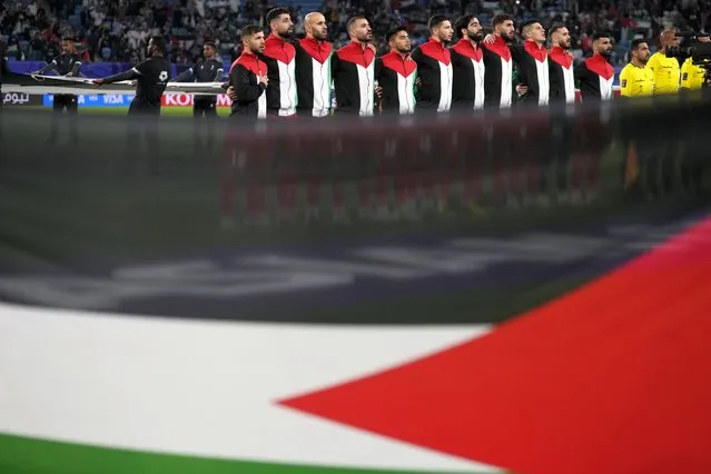 Players of team Palestine stand for their national anthem in front of a Palestinian flag prior to the start of the Asian Cup Group C soccer match between Palestine and United Arab Emirates at Al Janoub Stadium in Al Wakrah, Qatar, Thursday, January 18, 2024. (Photo by Thanassis Stavrakis/AP Photo)