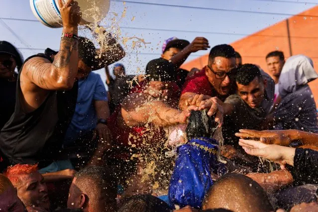 People are seen throwing rhum at the the statue of San Benito as a sign of devotion during the procession on December 27, 2023. The festivity of San Benito is celebrated in parts of Venezuela every 27th of December and especially in the city of Cabimas in the Zulia state, where a large procession takes place through the town for more than 13 kms carrying the statue of the saint, with thousands of devotees chanting, playing music and throwing rhum at it as a sign of devotion and to ask for favors to the saint. (Photo by Davide Bonaldo/Rex Features/Shutterstock)