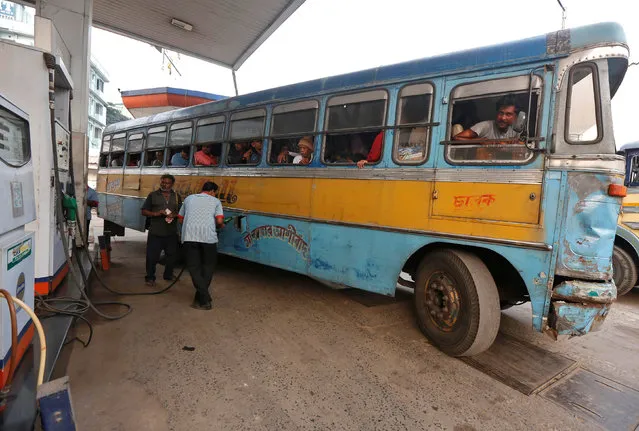 A worker fills a public bus with diesel as the bus driver and passengers look on, at a fuel station in Kolkata, India, February 1, 2017. (Photo by Rupak De Chowdhuri/Reuters)