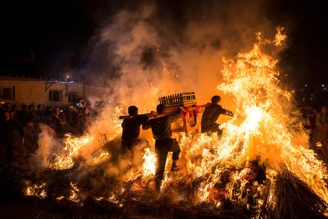 Men carrying a shrine jump over a bon fire, which means a wish for good luck during a traditional Chinese lunar new year celebration in Jieyang, Guangdong province, China, February 2, 2017. (Photo by Reuters/China Daily)