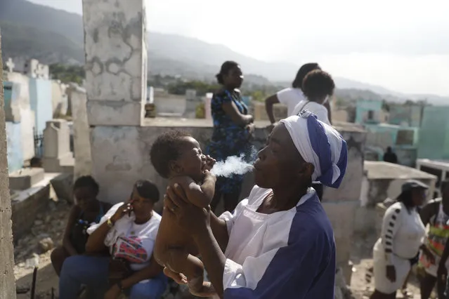 A Vodou priestess claiming to be possessed by a Gede spirit treats a sick baby during a ceremony honoring the Haitian Vodou spirit of Baron Samedi and Gede at the National Cemetery in Port-au-Prince, Haiti, Monday. November 1, 2021. (Photo by Joseph Odelyn/AP Photo)