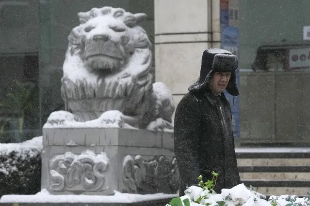 A security guard stands near a stone lion with a covering of snow in Beijing, China, Sunday, November 7, 2021. (Photo by Ng Han Guan/AP Photo)
