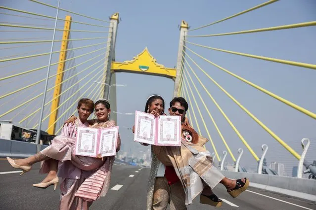 Two couples, Komsan Doichaiyapoom, 31, and Wilaiwan Pikulkaew, 30, and Paichayon Chaloemlom, 27 and Suwanna Buachubai, 27 pose for a picture after receiving their marriage license from an officer during a Valentine's Day celebration on newly constructed bridge paralleling the Rama IX Bridge in Bangkok, Thailand on February 14, 2024. (Photo by Chalinee Thirasupa/Reuters)