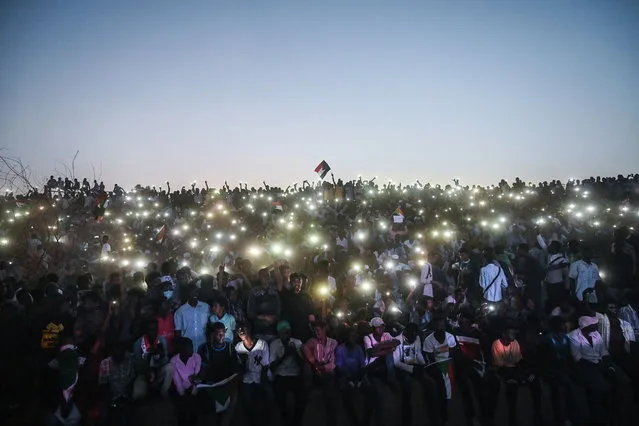 Sudanese protesters open their smartphones lights as they gather for a “million-strong” march outside the army headquarters in the capital Khartoum on April 25, 2019. Tens of thousands of protesters converged from all directions on Sudan's army headquarters after calls for a “million-strong” demonstration to demand the ruling military council cede power. (Photo by Ozan Köse/AFP Photo)