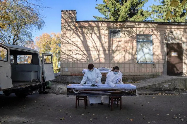 Medical staff prepare a coffin for a body of a patient who died of coronavirus at the morgue of the city hospital 1 in Rivne, Ukraine, Friday, October 22, 2021. In Rivne, 300 kilometers (190 miles) west of Kyiv, the city hospital is swamped with COVID-19 patients and doctors say the situation is worse than during the wave of infections early in the pandemic that severely strained the health system. Ukraine's coronavirus infections and deaths reached all-time highs for a second straight day Friday, in a growing challenge for the country with one of Europe's lowest shares of vaccinated people. (Photo by Evgeniy Maloletka/AP Photo)