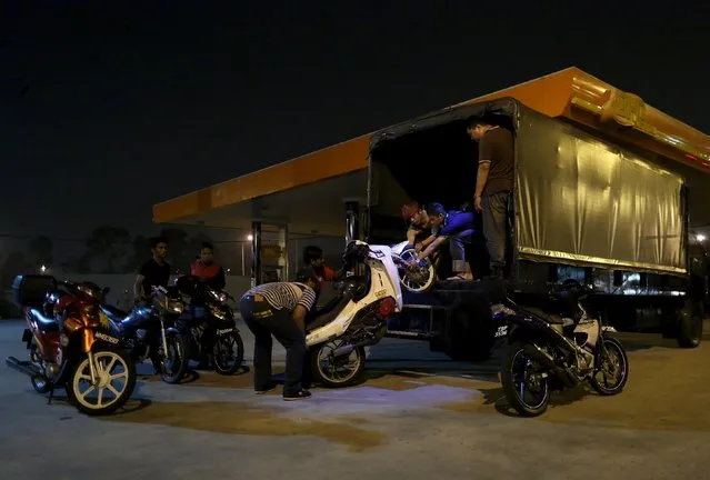 Men load their motorbikes onto a truck after they were confiscated by police on a highway in Kuala Lumpur, Malaysia, September 14, 2014. (Photo by Olivia Harris/Reuters)