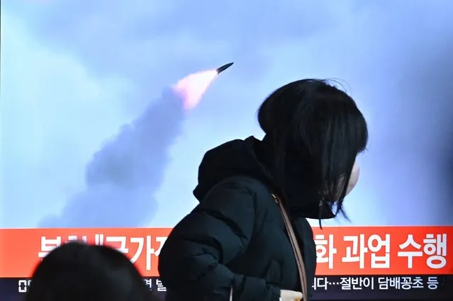 People walk past a television screen showing a news broadcast with file footage of a North Korean missile test, at a railway station in Seoul on January 11, 2022, after North Korea fired a “suspected ballistic missile” into the sea, South Korea's military said, less than a week after Pyongyang reported testing a hypersonic missile. (Photo by Anthony Wallace/AFP Photo)
