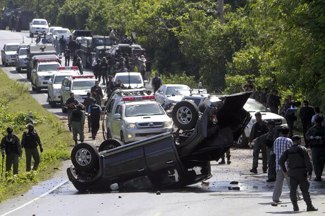 Security forces inspect the site of a bomb attack on police in the troubled southern province of Narathiwat March 30, 2014. Two policemen were killed and three wounded in a roadside bomb attack as they were traveling to provide security to the polling stations for Sunday's Senate elections, local media reported. (Photo by Surapan Boonthanom/Reuters)