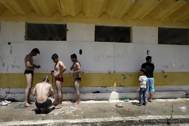 Migrants take a shower at a refugee and migrant camp in the village of Moria on the northeastern Greek island of Lesvos on Wednesday, June 17, 2015. The Aegean island has borne the brunt of a huge influx of migrants from the Middle East, Asia and Africa crossing from Turkey to nearby Greek islands. More than 50,000 migrants have arrived in Greece so far this year. (AP Photo/Thanassis Stavrakis)