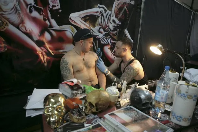 A tattoo artist works on a client during the second International Tattoo Festival in Sochi, Russia, April 23, 2016. (Photo by Kazbek Basayev/Reuters)