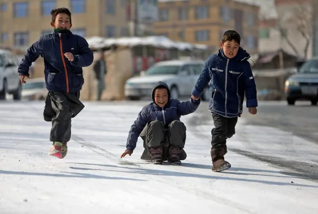 Afghan children play on a snow-covered road after a snowfall in Kabul, Afghanistan, December 16, 2021. (Photo by Ali Khara/Reuters)