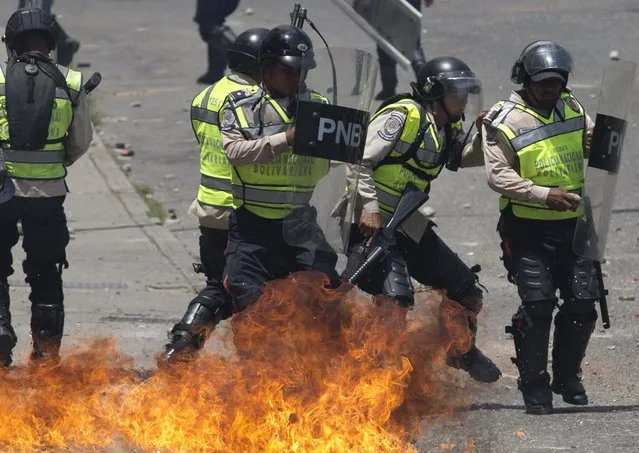 Bolivarian National Police officers move away after a gasoline bomb, launched by demonstrators, lands close during a protest in Caracas, Venezuela, Thursday, April 6, 2017. (Photo by Ariana Cubillos/AP Photo)