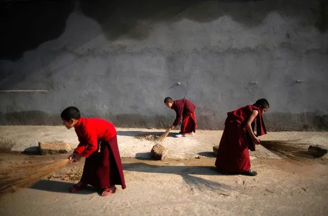 Young novice monks sweep a sidewalk along a road outside the Buddhist monastery in Godavari, Nepal on Monday, February 7, 2022. (Photo by Skanda Gautam/ZUMA Press Wire/Rex Features/Shutterstock)