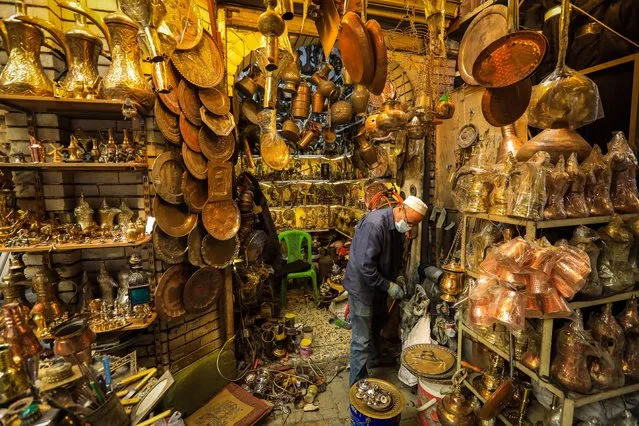 A copper master and his copper products are seen at Coppersmith Bazaar in Baghdad, Iraq on March 15, 2022. In the Coppersmiths' Bazaar on the famous Resid Street of the capital Baghdad, jugs, tea mugs, spoons, photo frames and other household materials decorated with copper embroideries are obtained after long efforts of copper masters. (Photo by Murtadha Al-Sudani/Anadolu Agency via Getty Images)
