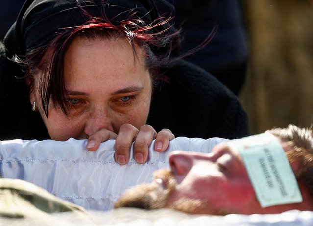 Svitlana looks at the body of her husband Kostiantyn Starovytskyi, a Ukrainian conductor, musician and serviceman, who was recently killed in a fight against Russian troops in Donetsk region, amid Russia's attack on Ukraine, during a funeral ceremony in the town of Brovary, outside of Kyiv, Ukraine on April 11, 2023. (Photo by Valentyn Ogirenko/Reuters)