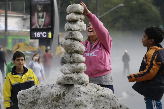 A woman makes a tower using ice from an overnight hailstorm in the Aclimacao neighborhood of Sao Paulo, Brazil, Monday, May 19, 2014. Some told local media their children hadn't seen hail or played with ice. (Photo by Nelson Antoine/AP Photo)