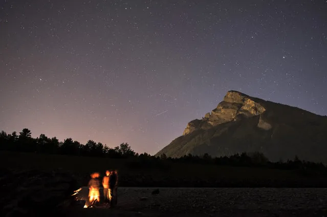 People gather at a fire with the Gonzen peak (1830 meters above sea level) in the background in Balzers, Liechtenstein, 06 May 2016 (issued 07 May). (Photo by Gian Ehrenzeller/EPA)