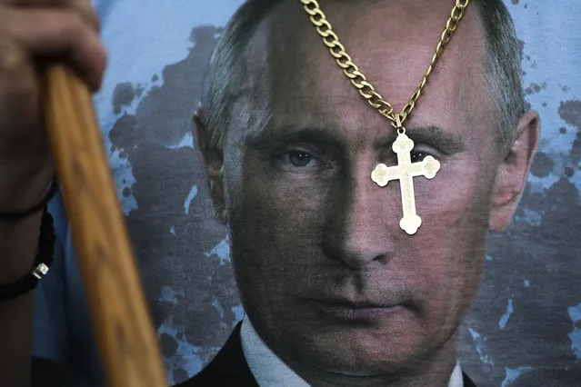 A man wears a cross and a shirt with the portrait of Russian President Vladimir Putin as he arrives for an event commemorating the end of World War II 72 years ago, at the Soviet War memorial at the district Tiergarten in Berlin, Tuesday, May 9, 2017. Thousands of people most of them with Russian roots or Russians living in Germany attend the annual celebrations marking the victory over Nazi Germany and the end of the WWII at the Soviet war memorials and cemeteries in the German capital. (Photo by Markus Schreiber/AP Photo)