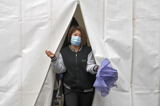 A woman wearing a face mask to help protect from the coronavirus walks out from a tent after getting a COVID-19 test, Tuesday, March 29, 2022, in Beijing. A two-phase lockdown of Shanghai's 26 million people is testing the limits of China's hard-line “zero-COVID” strategy, which is shaking markets far beyond the country's borders. (Photo by Andy Wong/AP Photo)