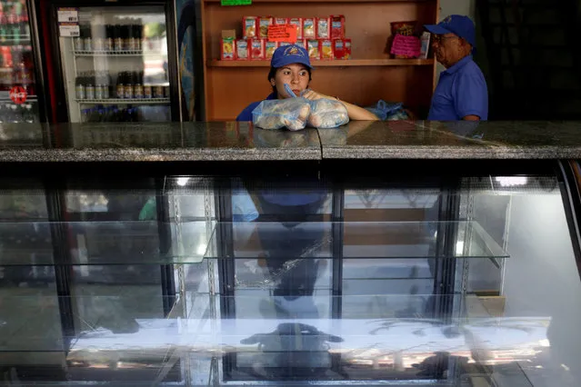 A saleswoman holds bags of bread as she waits for customers at bakery in Caracas, Venezuela March 17, 2017. (Photo by Marco Bello/Reuters)