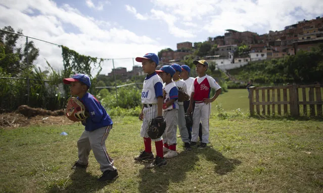In this August 12, 2019 photo, a young baseball player prepares to catch a ball during a practice at Las Brisas de Petare Sports Center, in Caracas, Venezuela. More than 100 boys train daily on the baseball field using old bats, balls and gloves, in hopes of achieving a professional baseball career in the United States. (Photo by Ariana Cubillos/AP Photo)