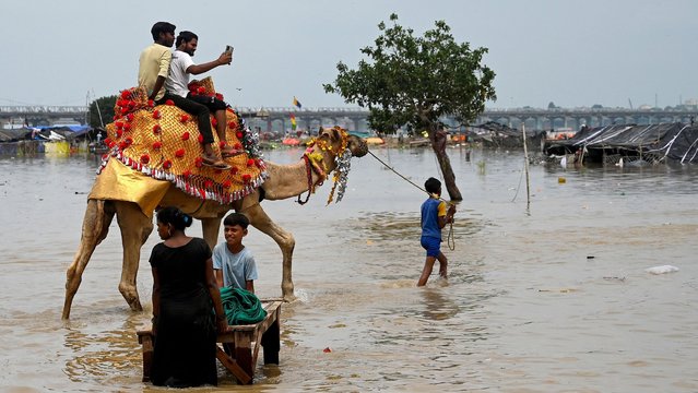 Men ride a camel across the flood waters on the banks of river Ganges in Prayagraj on August 6, 2024, after rise in water levels during the monsoons. (Photo by Sanjay Kanojia/AFP Photo)