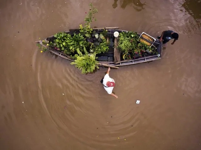 People transport their plants in a boat through a flooded street in the Jukyty neighborhood, in Asuncion, Paraguay, Thursday, April 4, 2019. More than 20,000 people in Paraguay have been evacuated after torrential rains caused extensive flooding. (Photo by Jorge Saenz/AP Photo)