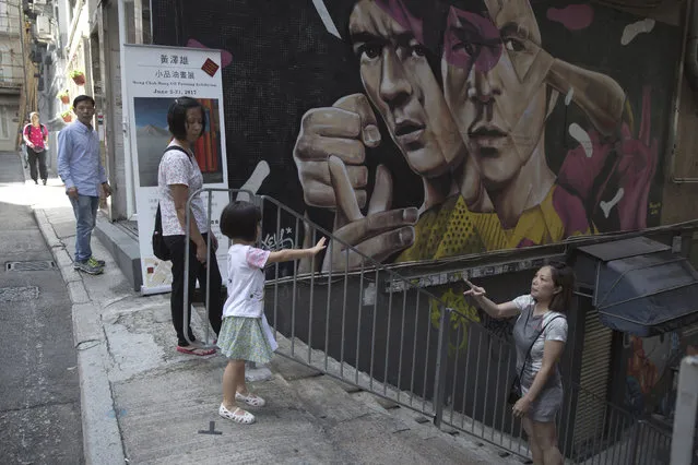 In this June 7, 2017, photo, a mother and daughter play on stairs with wall painting of martial arts star Bruce Lee in the background, in Central district, Hong Kong. (Photo by Kin Cheung/AP Photo)