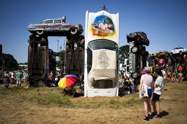 Festival goers gather around Car Henge at the Glastonbury Festival in Worthy Farm, Somerset, England, Thursday, June 22, 2023. (Photo by Scott Garfitt/Invision/AP Photo)