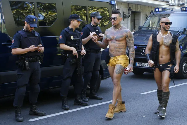 Participants walk past police officers before a Gay Pride demonstration and parade, the climax of the 10-day WorldPride festivities, in Madrid, Spain, Saturday, July 1, 2017. Madrid is celebrating WorldPride 2017, a colorful mixture of vindication for sexual and gender diversity and all-night partying. (Photo by Paul White/AP Photo)