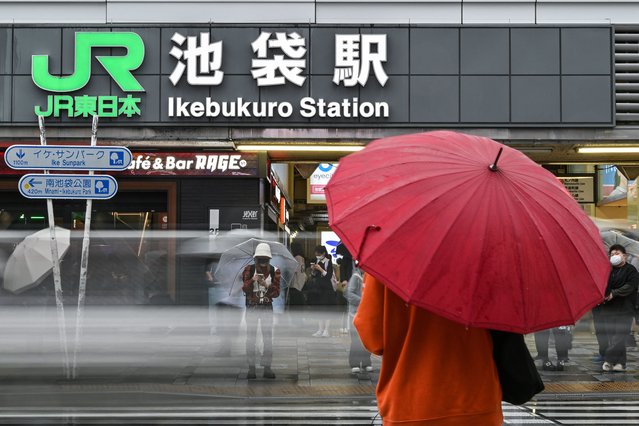 This photo taken on June 18, 2024 shows people using umbrellas to shield from the rain outside Ikebukuro station, one of 30 stations along the JR Yamanote Line in Tokyo. In service since 1885, the Yamanote Line is Tokyo's oldest, most important and most famous, with millions cramming onto the 35-kilometre (22-mile) route's distinctive green cars every day. (Photo by Richard A. Brooks/AFP Photo)