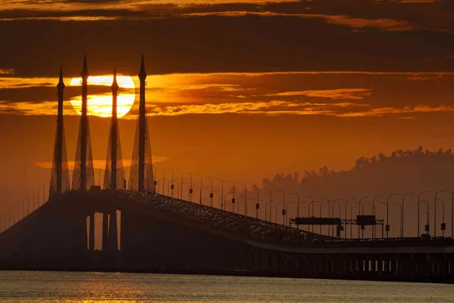 The sun rises as vehicles cross over the Penang Bridge on Penang island, Northern Malaysia, Friday, February 18, 2022. (Photo by Vincent Thian/AP Photo)