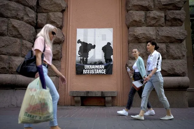 Women walk past a poster reading “Ukrainian resistance” in Kyiv, Ukraine, Monday, June 6, 2022. (Photo by Natacha Pisarenko/AP Photo)