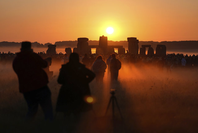 People watch the sun rise, as they take part in the Summer Solstice at Stonehenge in Wiltshire, Friday, June 21, 2024. (Photo by Andrew Matthews/PA Wire/PA via AP Photo)