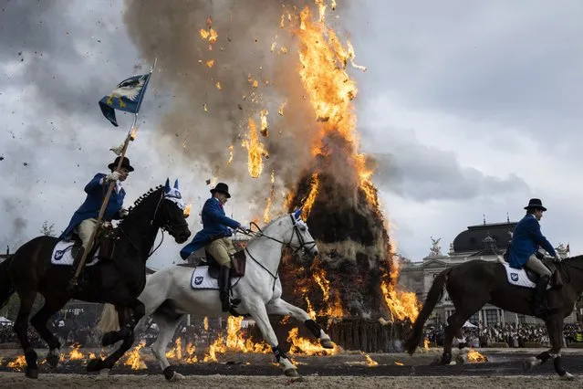 Members of guilds in historical uniforms parade on horseback past the burning “Boeoegg” figure on the Sechselaeuten place in Zurich, Switzerland, 25 April 2022. The Sechselaeuten (ringing of the six o'clock bells) is a traditional end of winter festival and the burning of the Boeoegg, a symbolic snowman, at 6 pm. The faster the Boeoegg explodes, the hotter the summer will be, according to traditional weather rules. (Photo by Ennio Leanza/EPA/EFE)
