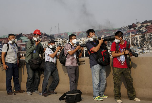 Photographers wearing masks stand near the site of last week's explosions during a government-organised media trip to Binhai new district in Tianjin, China, August 17, 2015. (Photo by Kim Kyung-Hoon/Reuters)