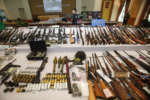 A soldier stands next to illegal weapons seized in raids following the May 22 military coup, during a news conference at a military barracks in Bangkok July 29, 2014. The weapons, ranging from shotguns to homemade bombs, and ammunition were seized during a search and arrest operation which took place from June 26 to July 29. Authorities also arrested 2,779 suspects during the operation, according to the Public Relation Center of the Peace and Order Maintaining Task Force. (Photo by Athit Perawongmetha/Reuters)