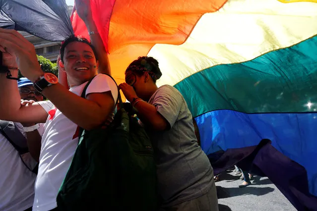 Revellers smile as they hold a giant rainbow during the gay pride parade in Caracas, Venezuela July 3, 2016. (Photo by Carlos Jasso/Reuters)