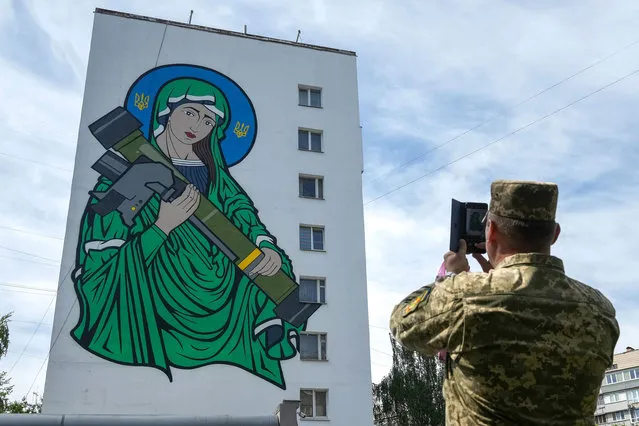 Ukrainian soldiers take pictures of a mural titled “Saint Javelin” dedicated to the British portable surface-to-air missile has been unveiled on the side of a Kyiv apartment block on May 25, 2022 in Kyiv, Ukraine. The artwork by illustrator and artist Chris Shaw is in reference to the Javelin missile donated to Ukrainian troops to battle against the Russian invasion. Following Russia's retreat from areas around the Ukrainian capital, signs of normal life have returned to Kyiv, with residents taking advantage of shortened curfew hours, businesses reopening, and foreign countries promising to return their diplomats. (Photo by Christopher Furlong/Getty Images)