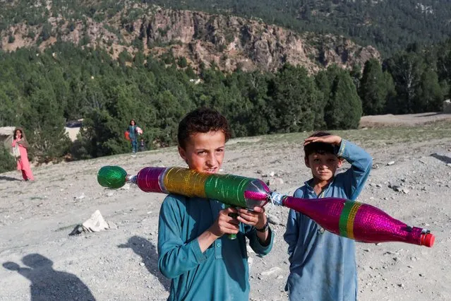 An Afghan boy plays with hand made RPG toy in the quake-hit area in the Spera district of Khost province, Afghanistan, June 26, 2022. (Photo by Ali Khara/Reuters)