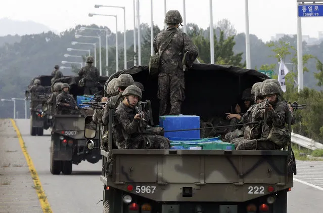 South Korean army soldiers ride on trucks in Paju, south of the demilitarized zone that divides the two Koreas, South Korea, Monday, August 24, 2015. Marathon negotiations by senior officials from the Koreas stretched into a third day on Monday as the rivals tried to pull back from the brink. South Korea's military, meanwhile, said North Korea continued to prepare for a fight, moving unusual numbers of troops, hovercraft and submarines to the border. (Photo by Ahn Young-joon/AP Photo)